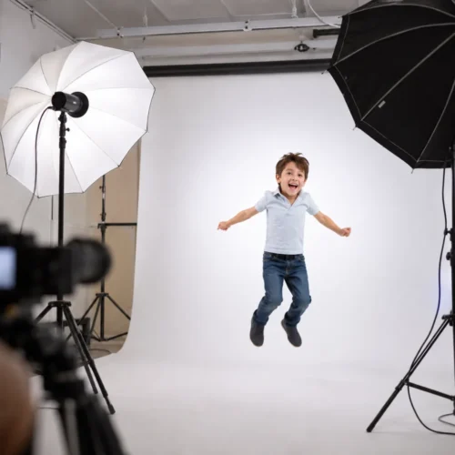 Lachender Junge springt beim Casting-Fotoshooting vor weißer Hohlkehle im Fotostudio – Die Kinderagentur